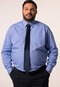 Lichtblauwe overhemden met een kraag en een borstzak, gecombineerd met een donkere stropdas. Het overhemd heeft een zachte textuur en lange mouwen.