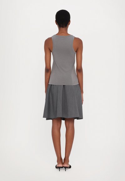 Gray tank top with a fitted design, paired with a gray pleated skirt that falls around mid-calf. Classic black heels complement the outfit.