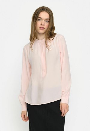 Lys rosa bluse i et blødt, gennemsigtigt stof med mandarinkrave, knaplukning og lange ærmer, parret med en sort nederdel.