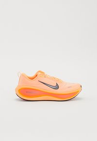 Helle orange Nike-Laufschuhe mit schwarzem Swoosh, dickem gepolstertem Schuhsohle mit der Aufschrift "ZoomX" und Schnürdesign auf einfachem Hintergrund.