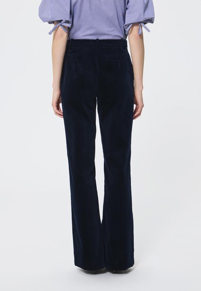 Jūriniai pločio kelnės, pagamintos iš minkštos medžiagos, turinčios lygų tekstūrą, tradicinius kišenes ir pritaikytą juosmenį.