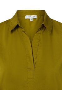 Olivgrüne Bluse mit spitzem Kragen, V-Ausschnitt und Etikett mit der Aufschrift "Marie Lund Kopenhagen 36" im Kragen.