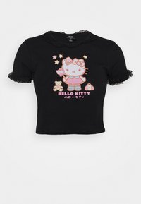 Černý krátký rukáv s krajkovým lemem, s pastlovou Hello Kitty, která drží hůlku, plyšového medvídka, hvězdy a textem níže.