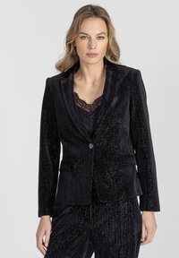 Czarna aksamitna marynarka w pionowy, fakturowany wzór w prążki, z pojedynczym zapięciem na guzik i dwoma przednimi kieszeniami.