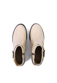 Stivali alla caviglia in pelle beige con suole in gomma nera, dettaglio della fibbia laterale, superficie liscia e punte arrotondate.