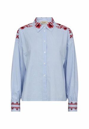 Világoskék és fehér csíkos hosszú ujjú ing, piros virágos hímzéssel a vállakon, galléron és mandzsettákon, valamint elöl fehér gombokkal.