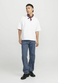Hvit bomulls t-skjorte med korte ermer, sammen med blå denimjeans. Mørkebrune lærsko og et maroon skjerf rundt halsen.