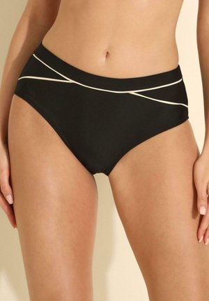Kobieta w czarnych dolnych partiach bikini z białymi skośnymi detalami wykończenia na biodrach, pokazana od talii do górnej części ud.