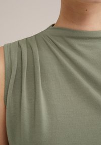 Groene blouse met korte mouwen, gemaakt van zachte, gedrapeerde stof met subtiele plooien rond de schouders en een ronde hals. Soepele textuur, casual ontwerp.