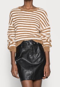 Braun- und weiß gestreifter, flauschiger Pullover mit weitem Halsausschnitt, kombiniert mit einem hochgeschnittenen schwarzen Lederrock mit tailliertem Gürtel.