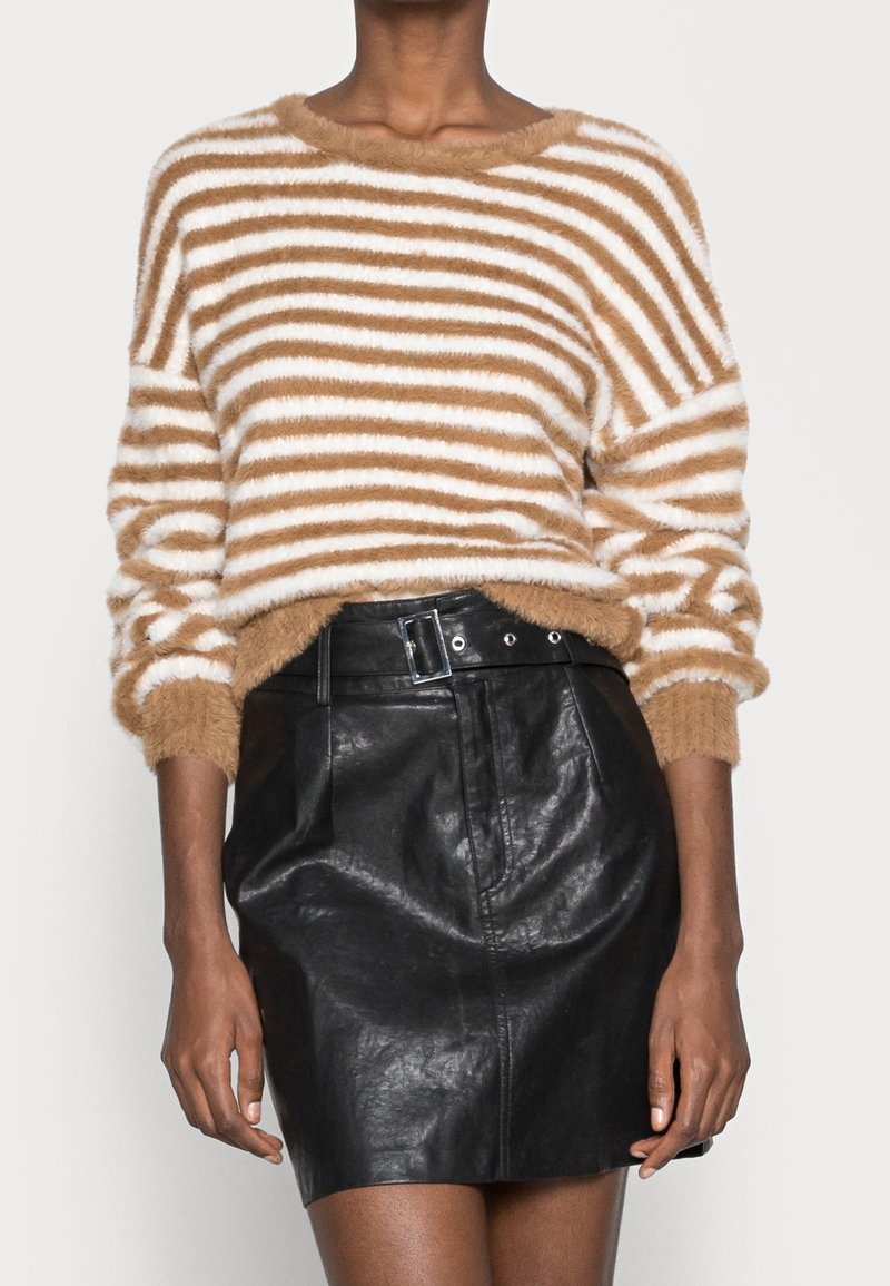 Braun- und weiß gestreifter, flauschiger Pullover mit weitem Halsausschnitt, kombiniert mit einem hochgeschnittenen schwarzen Lederrock mit tailliertem Gürtel.