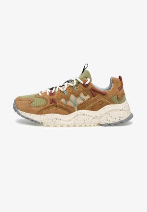 Brązowy i oliwkowo-zielony but sportowy z białymi sznurowadłami, niebieskimi i czerwonymi akcentami, teksturowaną, nakrapianą podeszwą oraz pętelką na pięcie i języku.