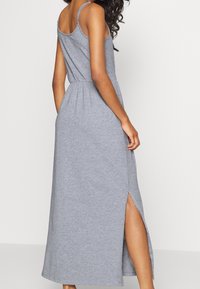 Graues Maxikleid aus weichem Stoff, mit dünnen Trägern, einem taillierten Bund und seitlichen Schlitzen für mehr Bewegungsfreiheit.