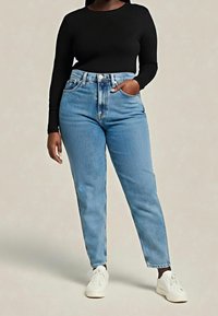 Niebieskie jeansy z wysokim stanem o prostych nogawkach, jasna tekstura denimu, design z pięcioma kieszeniami oraz czarna bluzka z długim rękawem. Całość dopełniają białe trampki.