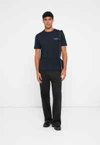 Navy short-sleeve t-shirt with a logo on the chest, paired with black trousers and black shoes, featuring a simple and clean design.