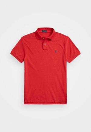 Camiseta polo roja de manga corta con cuello y dos botones, con un pequeño logo azul bordado en el pecho izquierdo.