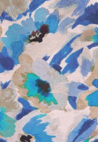 Motif floral bleu, vert, beige et blanc sur tissu texturé avec des formes de fleurs abstraites et des détails sombres au centre.