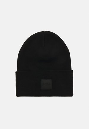 Black knitted beanie with a folded cuff, featuring a textured fabric and a small black logo patch on the front.