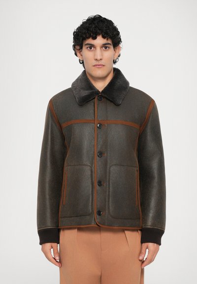 Veste extérieure marron avec un col en fausse fourrure grise douce, fermeture à boutons et coutures marron contrastantes, dotée de deux poches avant.