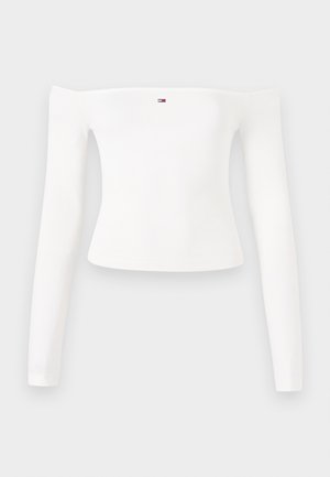 Haut à manches longues blanc à côtes avec un design décolleté. Présente un petit logo sur la poitrine. Texture lisse et coupe ajustée.