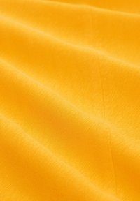 Gelbes Gewebe mit einer strukturierten Oberfläche, das gewellte Muster aufweist. Das Material wirkt glatt und leicht und fällt anmutig.