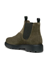 Botines de ante verde oliva con paneles laterales elásticos, lengüetas y suela de goma negra. El diseño presenta una punta redondeada y acentos texturizados.