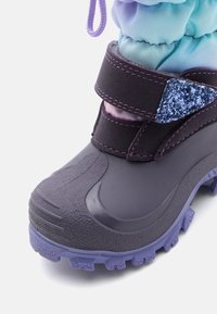 Violetinis nepralaidus vandeniui batas su tekstūruota gumine išore, pritvirtintas plačiu Velcro dirželiu su blizgančiomis detalėmis, turintis sugriebimo padas.