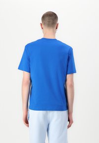 Μπλε βαμβακερό T-shirt με στρογγυλή λαιμόκοψη και κοντά μανίκια, με λεία υφή και χωρίς ορατά λογότυπα ή σχέδια στο πίσω μέρος.