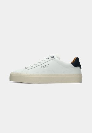 Baskets blanches en cuir avec une épaisse semelle crème, un accent de talon bleu marine et un logo sur le côté. Texture lisse, design minimaliste, avec un système de laçage.
