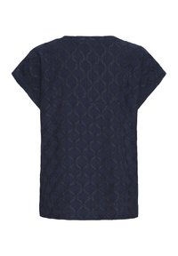 Blouse à manches courtes en dentelle bleu marine avec un motif ajouré floral et géométrique, vue de dos sur fond blanc.