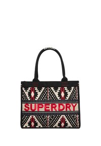 Canvas boodschappentas met zwart, rood en crèmekleurige geometrische patronen. Grote "SUPERDRY"-logo in rood met dubbele zwarte handvatten.