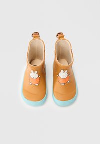 Bottes en caoutchouc marron à la cheville avec des semelles turquoise, présentant un design de lapin de dessin animé à l'avant. Texture lisse avec deux languettes de traction.