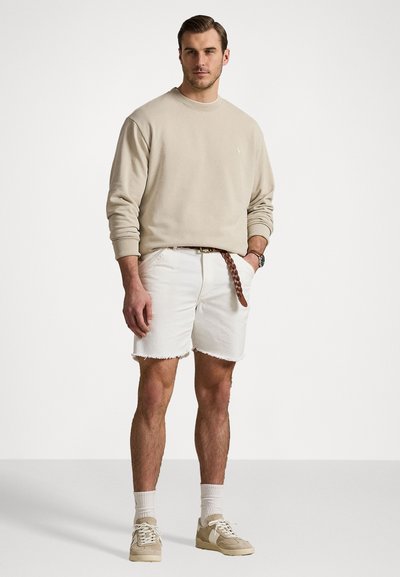 Beige pulóver, fehér farmer sort rojtos szegéllyel, fonott barna öv, világos sportcipő, és fehér rövid zokni. Szerelmes nyári öltözet.