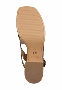 Bruna TOMS slide-sandaler med en texturerad sula, med justerbara remmar och cirkulärt hårdvarudetalj, märkta med storlek 37.
