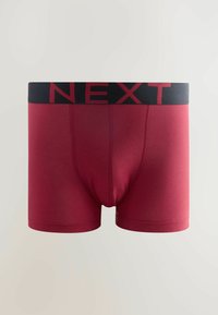 Boxeri scurți din bumbac roșu, cu un elastic negru la talie, pe care este inscripționat 'NEXT' cu litere roșii. Designul include cusături plate și o formă ajustată.