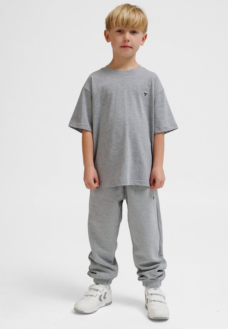 Graues Baumwoll-T-Shirt mit kurzen Ärmeln, passende graue Jogginghose und weiße Sneakers mit Riemen; einfaches Design, keine sichtbaren Muster oder Grafiken.