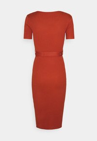Robe moulante côtelée de couleur orange brûlé avec des manches courtes et une taille mise en valeur par une ceinture assortie en tissu. Silhouette mi-longue.