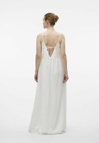 Robe maxi blanche avec un dos en dentelle, des bretelles ajustables et une texture fluide. Le dos présente un décolleté en V profond et un détail noué.