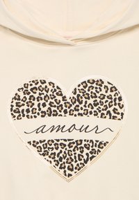 Cremefarbener Hoodie mit einem großen Herzdesign im Leopardenmuster und dem Wort "amour" in geschwungener Schrift in der Mitte.