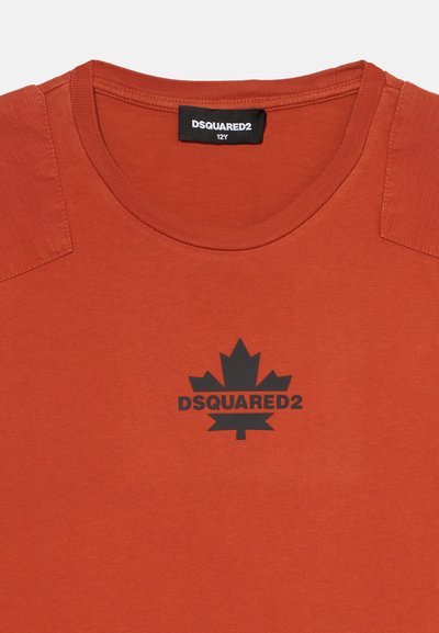 Μπλουζάκι σε πορτοκαλί απόχρωση της σκουριάς, με στρογγυλή λαιμόκοψη, μαύρο λογότυπο φύλλου σφενδάμου και επιγραφή DSQUARED2 στο στήθος, νευρώδεις επωμίδες και ετικέτα μεγέθους που γράφει 12Y.