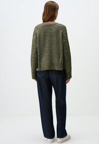 Groen gebreid sweater met textuur, ruime pasvorm, ronde halslijn en ribbelrand. Gecombineerd met donkerblauwe wijde jeans en witte sneakers.