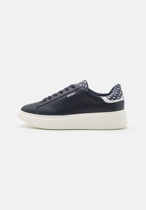 Niski granatowy sneaker z białą grubą podeszwą, wzorzystymi panelami na pięcie i języku, granatowymi sznurowadłami oraz logo "BOSS" po boku.