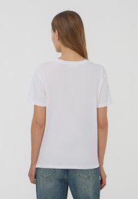 T-shirt bianco a manica corta con scollatura rotonda classica, realizzato in misto cotone, caratterizzato da una vestibilità rilassata e una trama liscia.