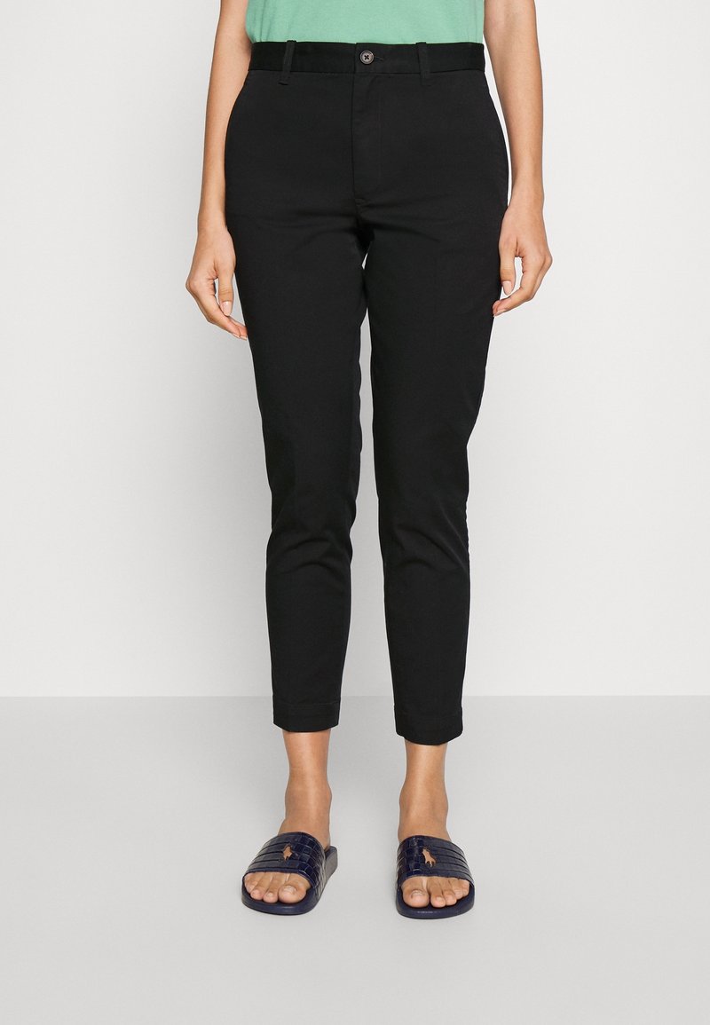 Svarta tapered byxor med knappstängning, bältesöglor och en mjuk twill-tyg. Kombinerat med mörka slidesandaler.