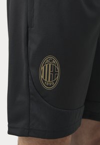 Svarta sportshorts med en guldig AC Milan-logotyp, slät textur, sidofickor och subtila mönstrade detaljer vid fållen.