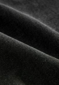 Černá texturovaná tkanina s diagonální vazbou, která vykazuje jemný, mírně lesklý povrch a subtilní variace v odstínech.
