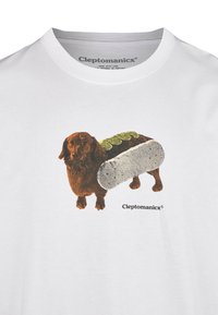 White cotton T-shirt featuring a graphic of a brown dog resembling a hot dog, with a textured bun and green toppings, branded "Cleptomanicx."