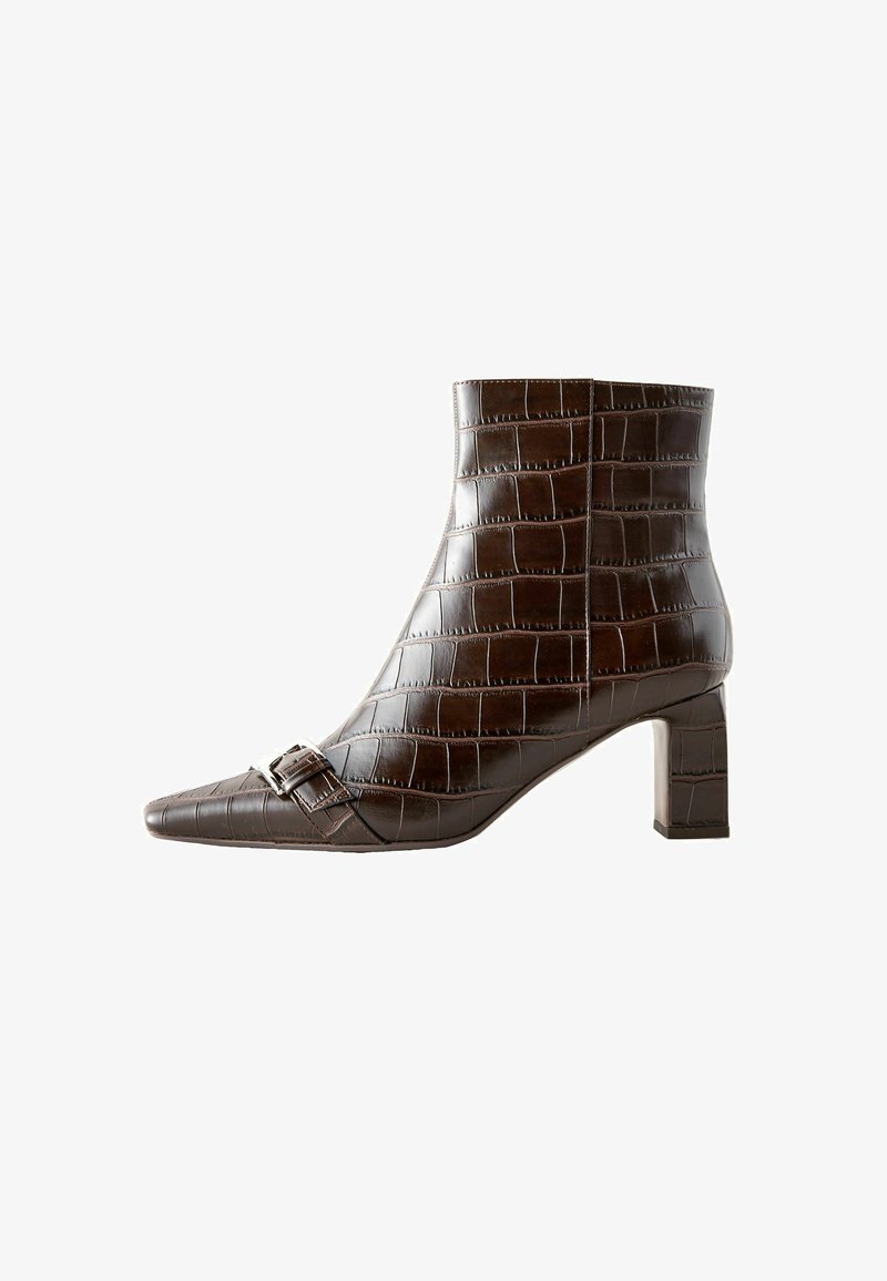 Bottine en cuir marron avec une texture crocodile, à bout pointu et talon bloc. Elle présente une boucle décorative sur le côté.