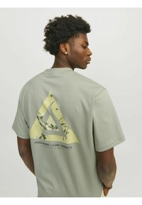 Grå kortærmet t-shirt med et trekantet grafisk print i gul og grøn, samt tekst på ryggen. Blødt bomuldsstof.