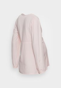 Camisola de manga longa rosa claro com cintura ajustada, decote redondo e mangas franzidas. Feita de um tecido suave e leve. Vista traseira.